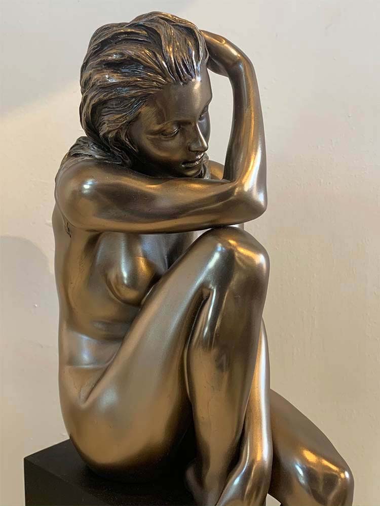 Elegant bronze-plated nude female sculpture on a display stand