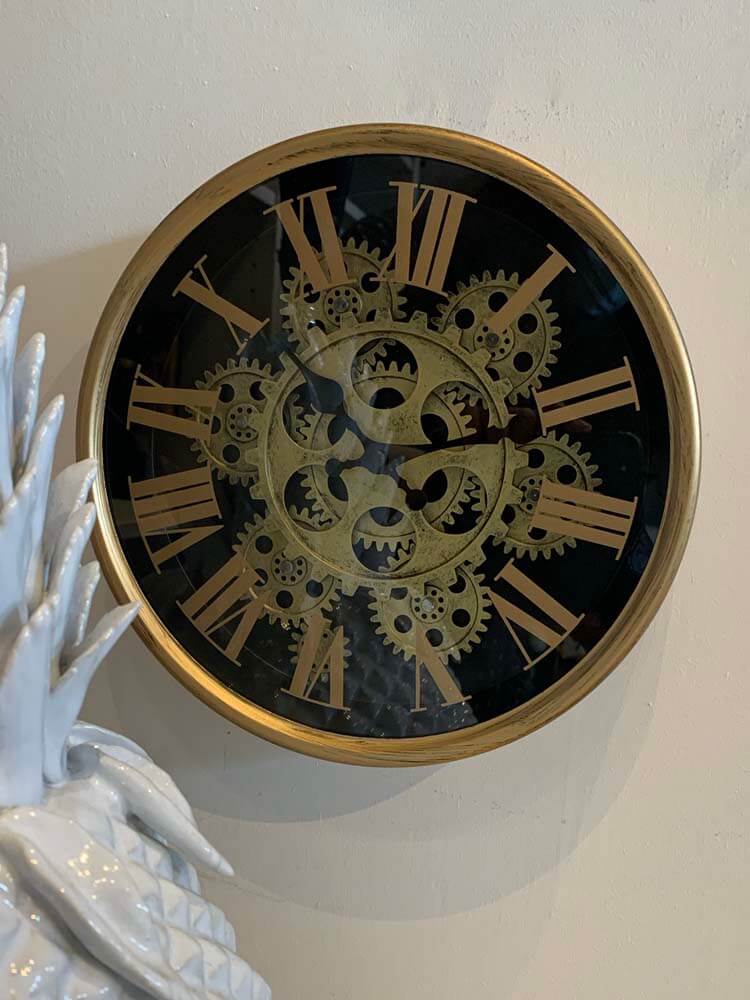 An unusual clock with a black face and moving gold mechanisms