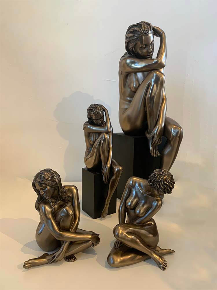 Elegant bronze-plated nude female sculptures on a display stand