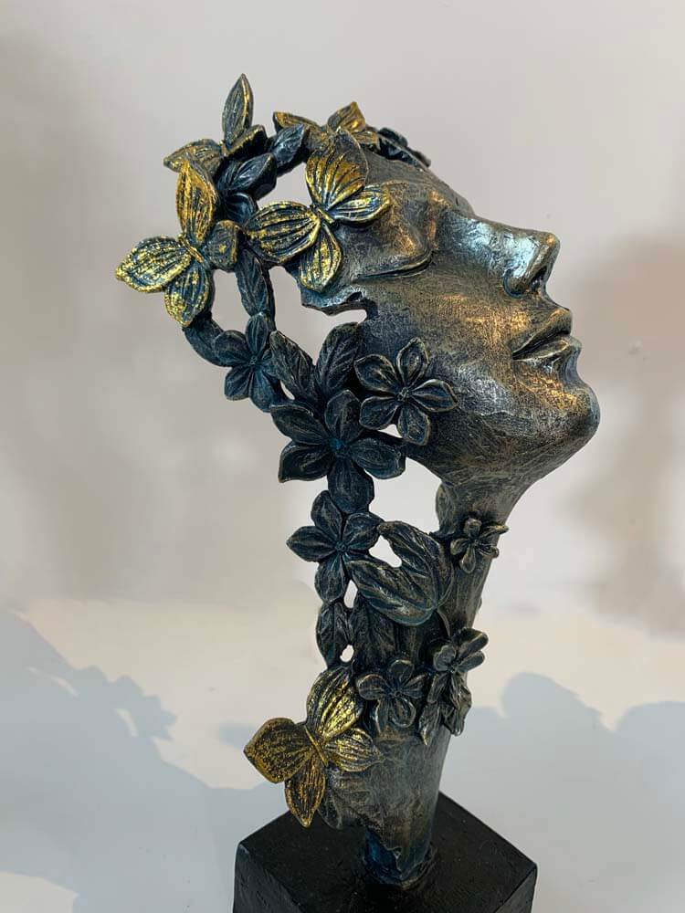Bronze sculpture of a face with floral and butterfly details by The Dutch Hospital