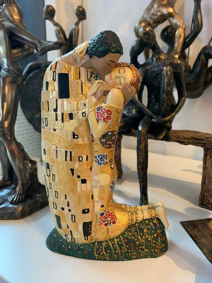 Statue of two figures embracing, inspired by Klimt's 'The Kiss', with a decorative pattern.