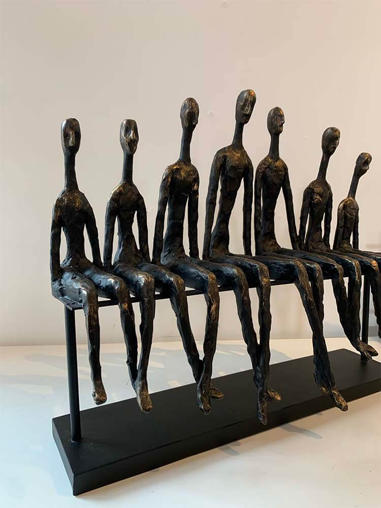 Seven seated figures lined up on a bench