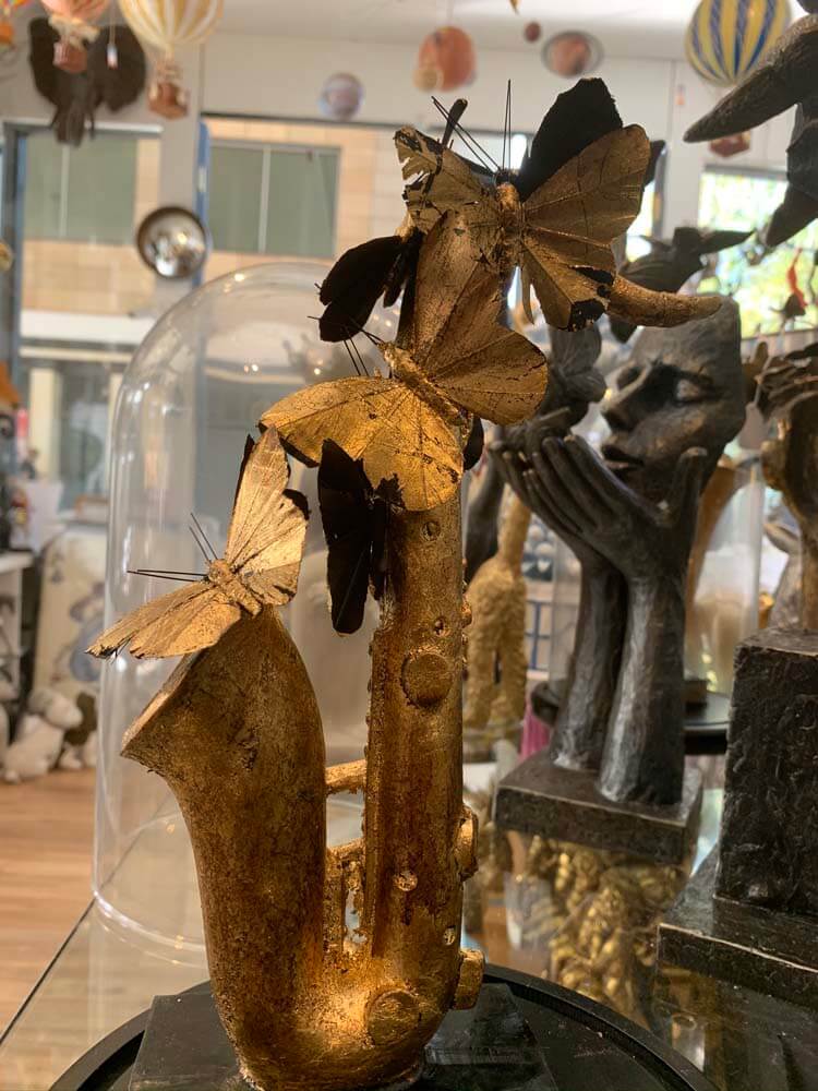 Gold saxophone sculpture inside a clear glass dome, black gold faux butterfly dome