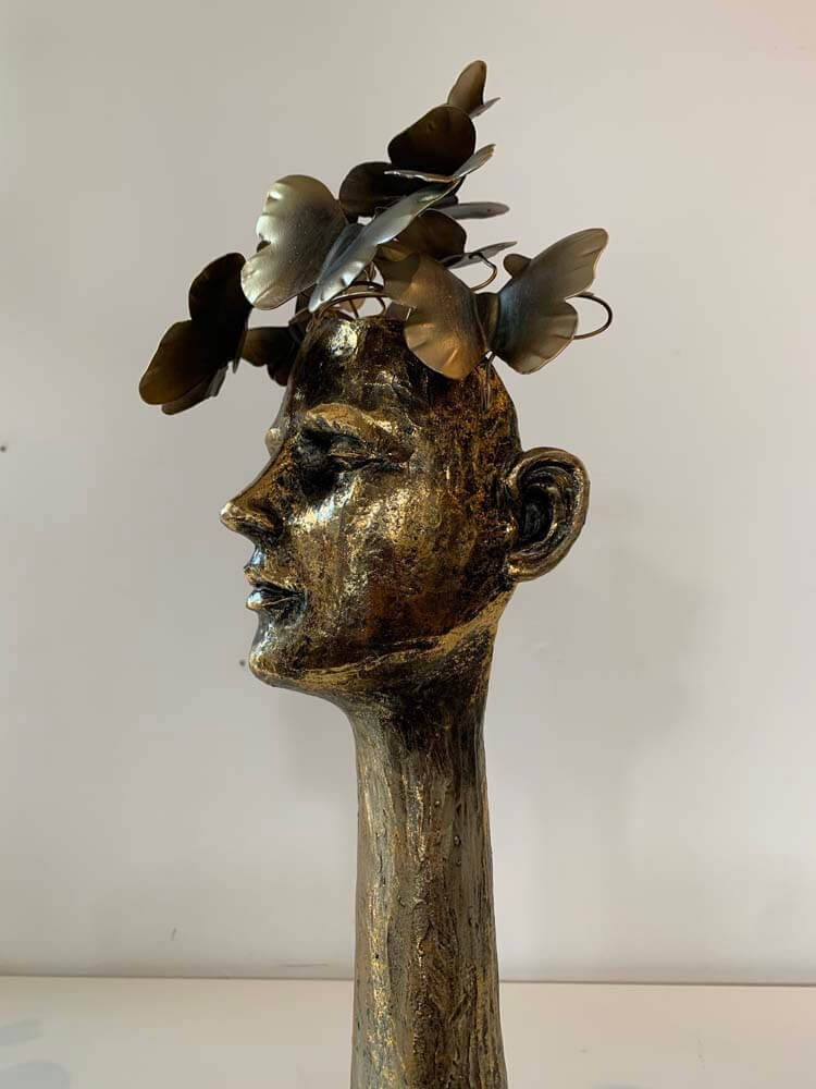 Bronze sculpture of a face with butterflies