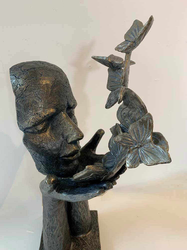 Bronze sculpture of a face with butterflies