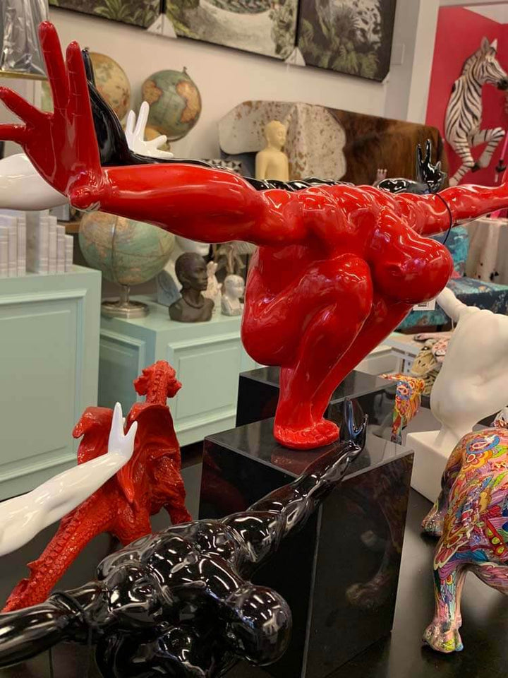 Red sculpture of a muscular male large figure with outstretched arms