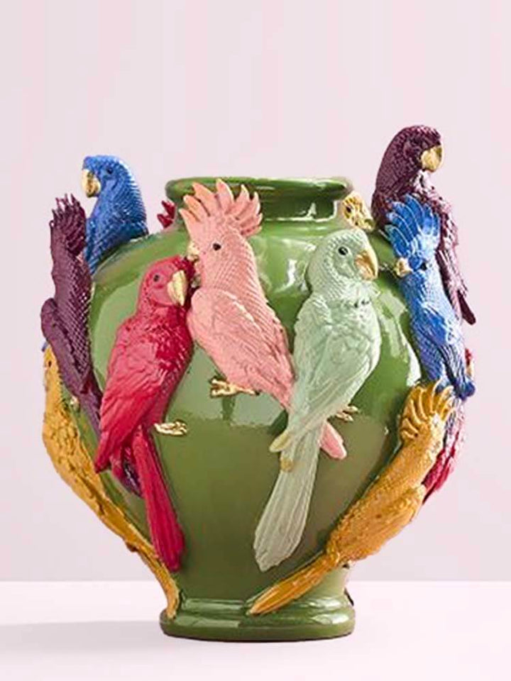Green vase with colorful parrot figurines 