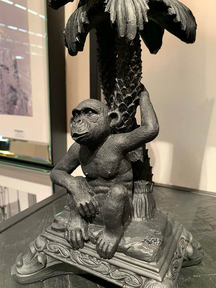 Statue of a monkey sitting under a palm tree, black monkey candle holder