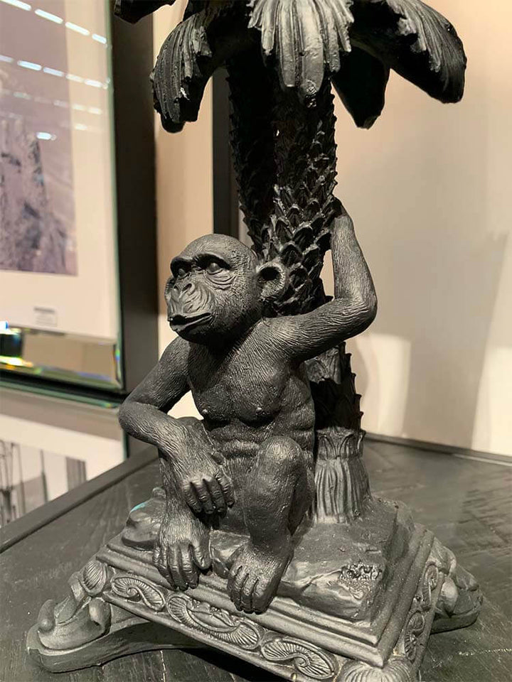 Statue of a monkey sitting under a palm tree, black monkey candle holder