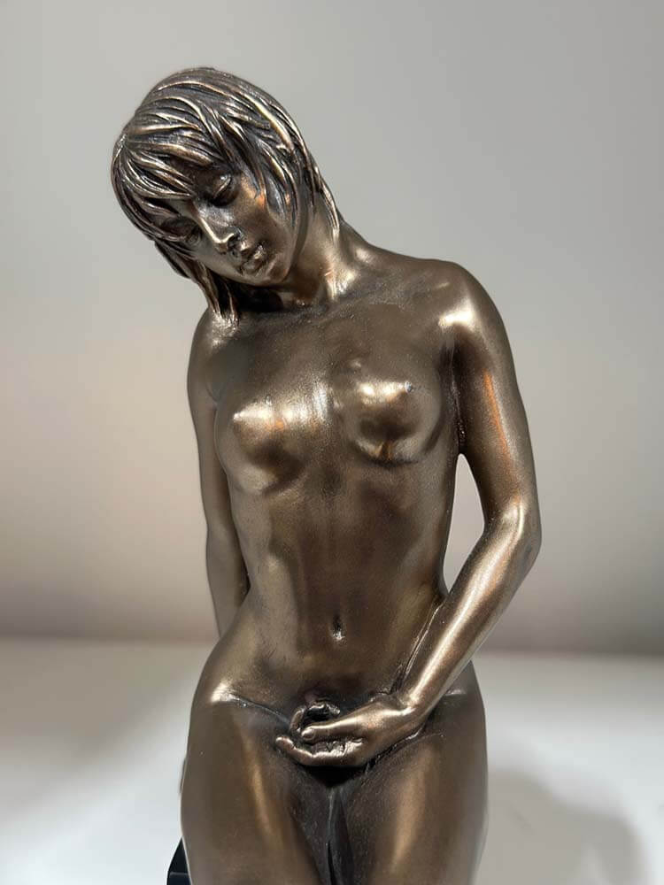 Bronze-plated nude female sculpture on a display stand