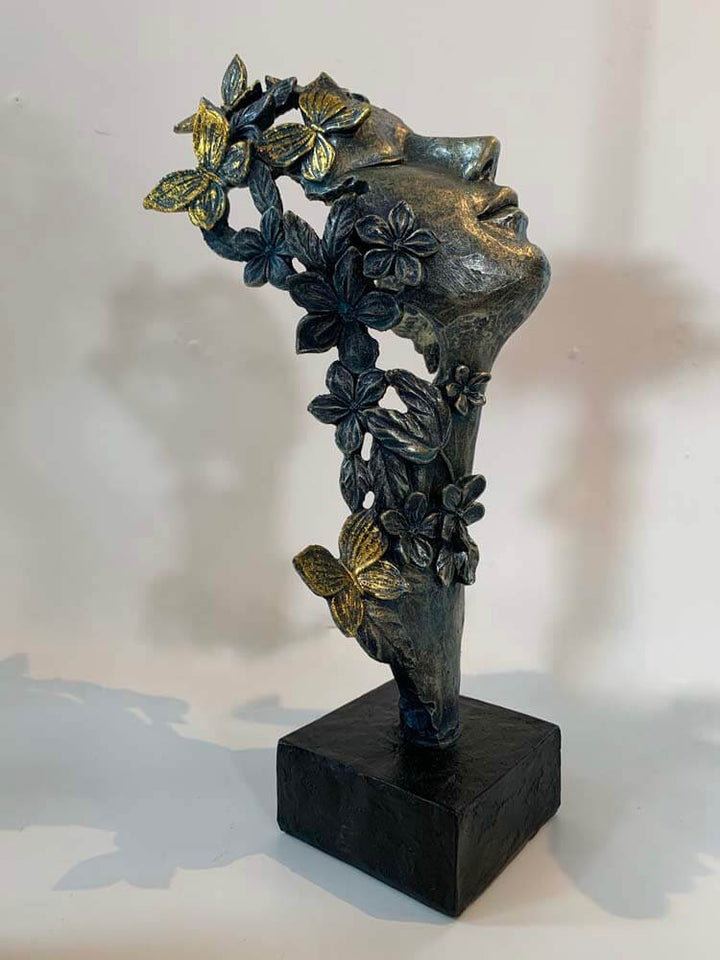 Bronze sculpture of a face with floral and butterflies 