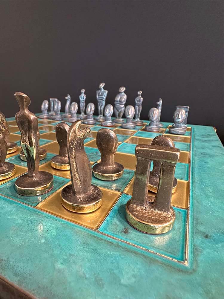 A decorative chess set with ornate pieces on a teal and gold board.