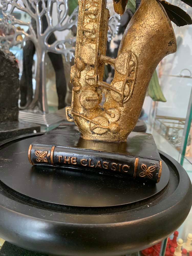 Gold saxophone sculpture inside a clear glass dome, black and gold faux butterfly 