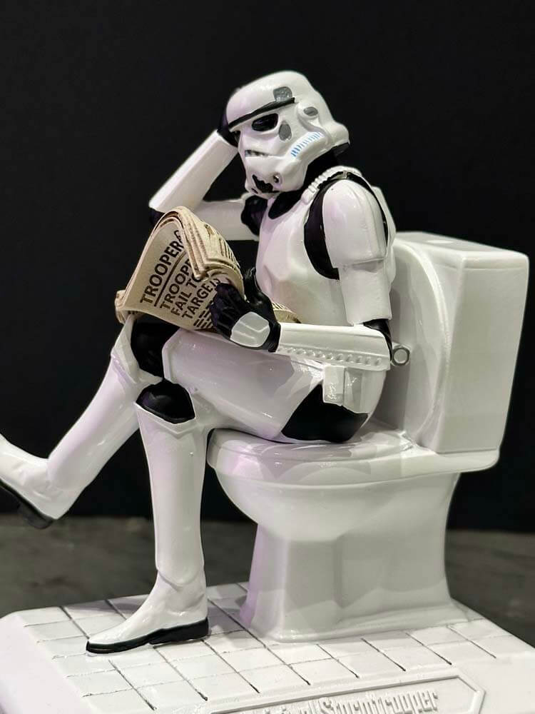 Stormtrooper figure sitting on a toilet reading a newspaper 
