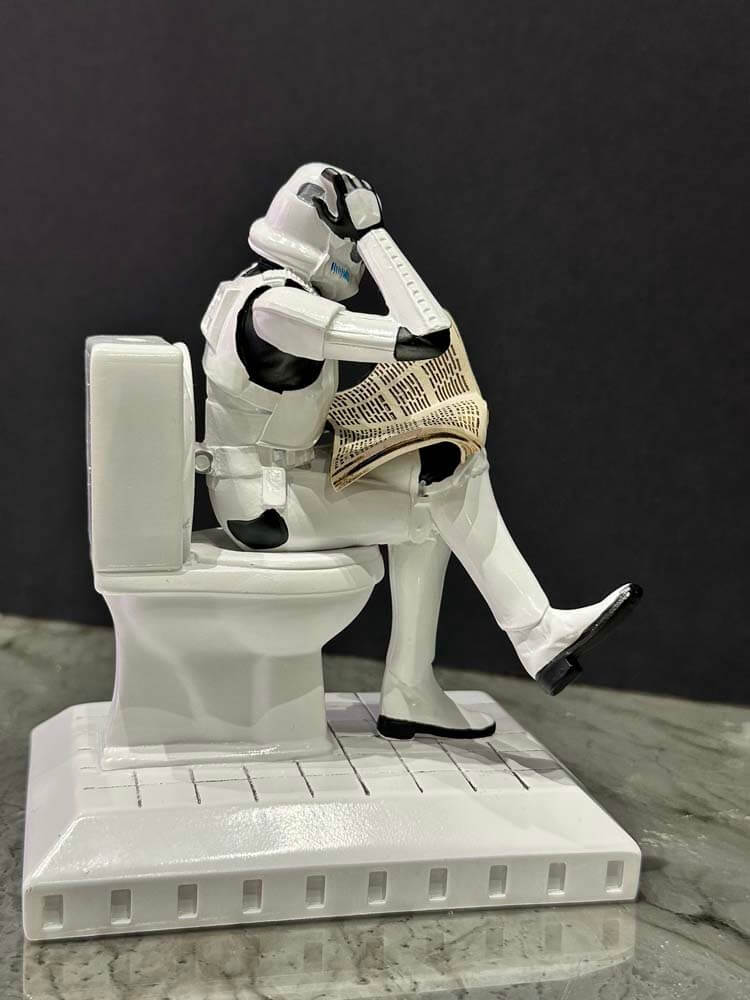Stormtrooper from Star Wars sitting on a toilet with a newspaper figurine 