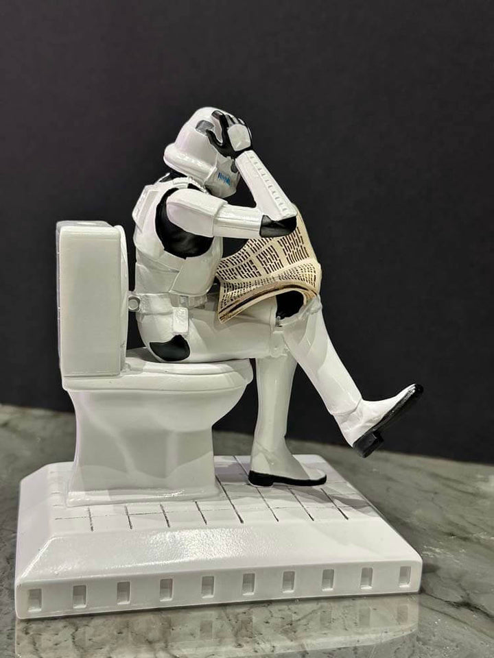 Stormtrooper from Star Wars sitting on a toilet with a newspaper figurine 