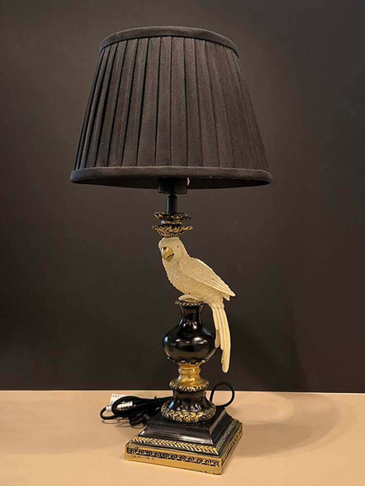 Decorative table lamp with a black pleated shade and parrot figurine 