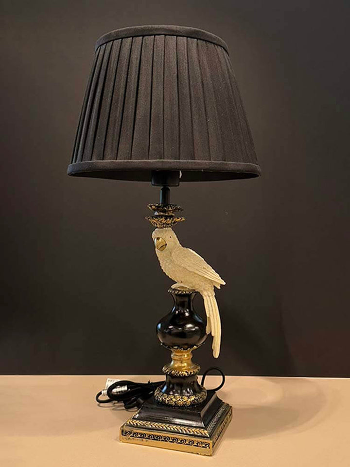 Decorative table lamp with a black pleated shade and parrot figurine 
