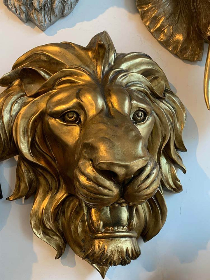 Large gold roaring lion wall head featuring intricate mane details and an antiqued metallic finish. Large gold finish roaring lion wall head decoration, regal African safari statement piece.